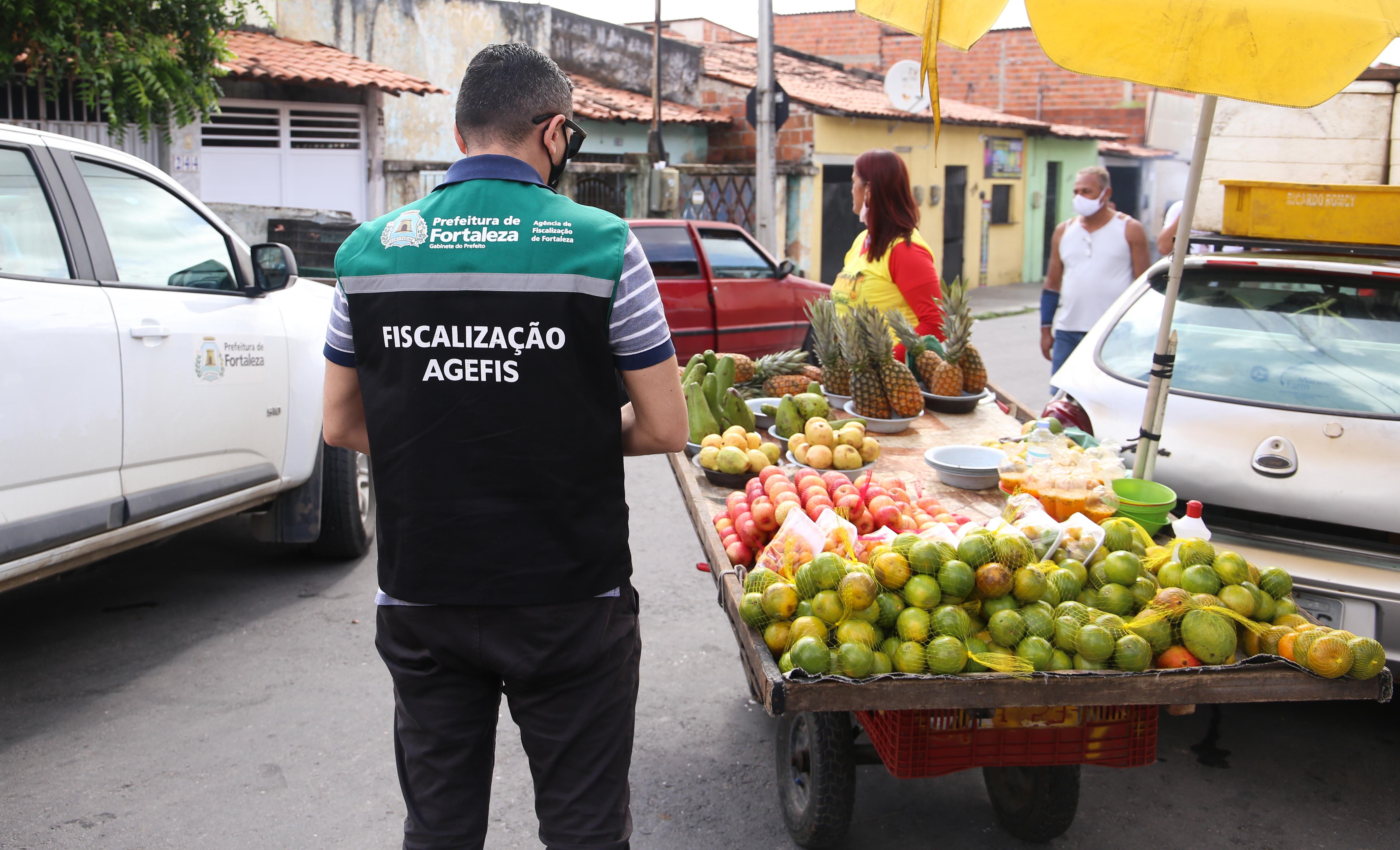 fiscal da agefis olha um carrinho de feira livre